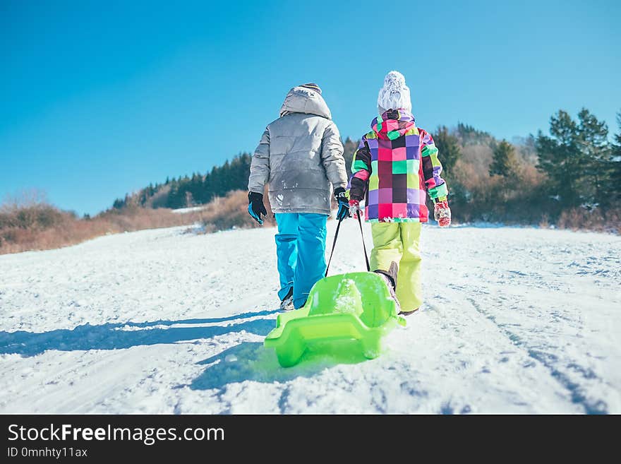 Little boy and girl carry the sled and enjoying winter sledding