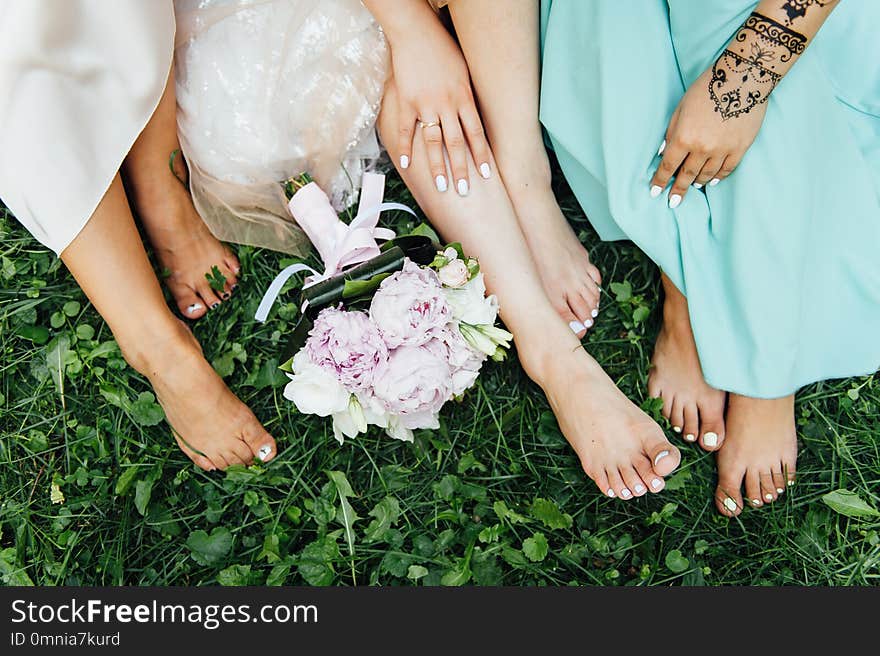 Feet of the bride and her bridesmaids on the green grassin summer time. wedding day. Feet of the bride and her bridesmaids on the green grassin summer time. wedding day