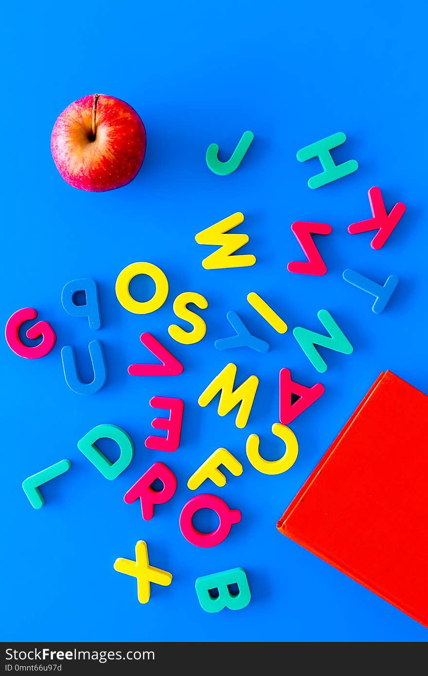 Children learn read concept. Hand hold plastic letters of toy alphabet on blue background top view