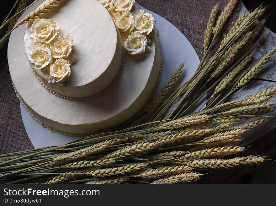 Wedding Cream Cake On Rustic Background. Beautiful Gourmet Tart Decorated With White Roses And Ears Of Wheat.