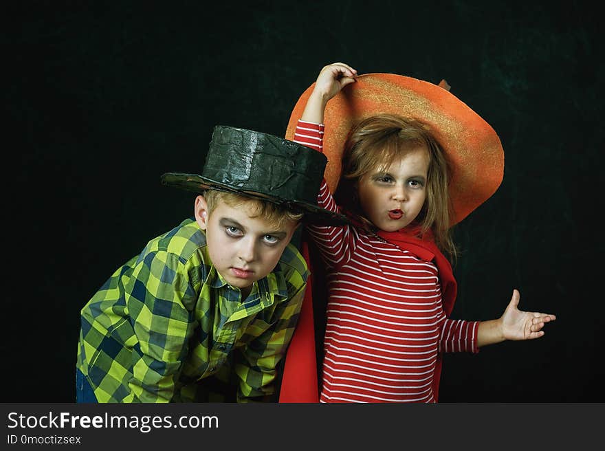 Brother and sister on Halloween. Funny kids in carnival costumes on dark background . Brother and sister on Halloween. Funny kids in carnival costumes on dark background .