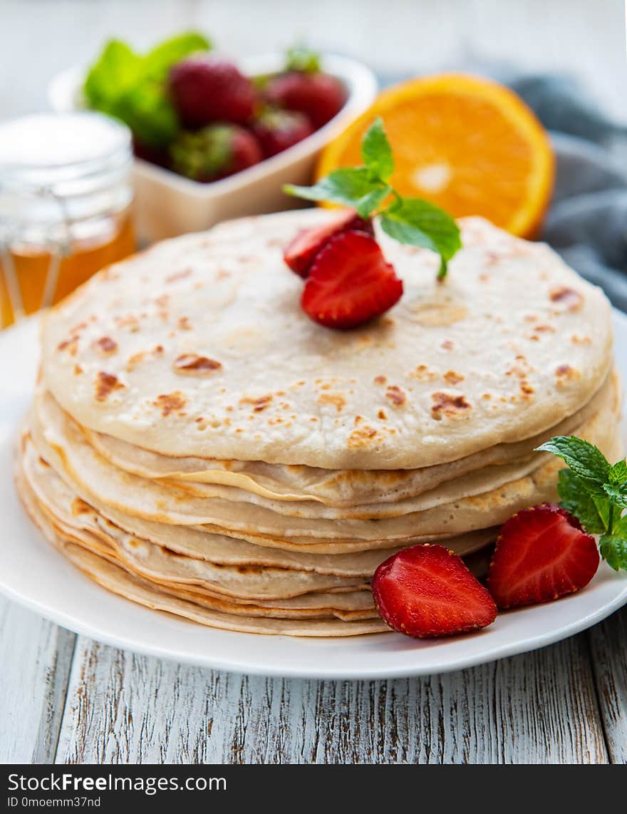 Delicious pancakes with strawberry on white wooden background