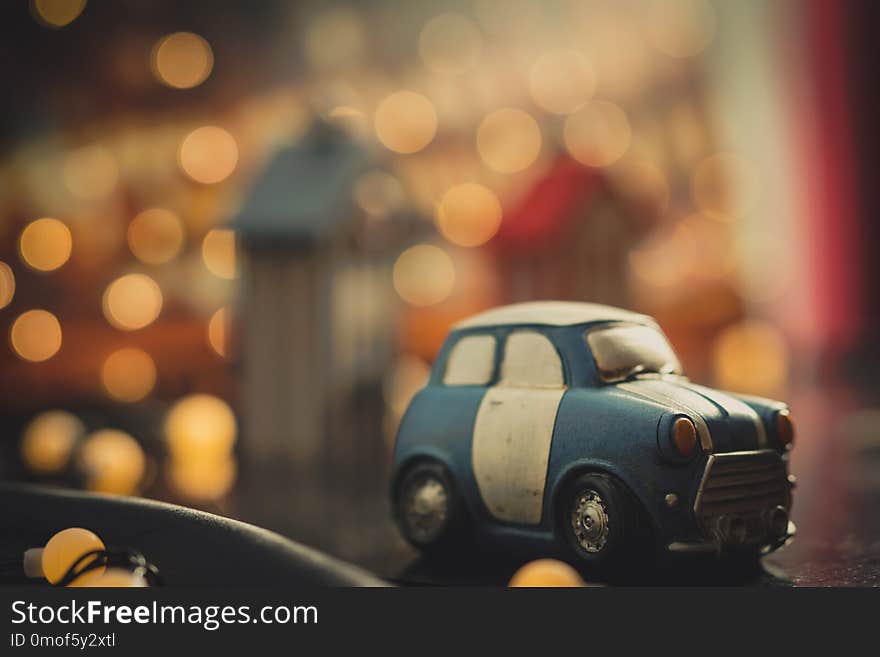 Blue and white cute cartoon car on orange bokeh background. Used car concept. Toy car model. Car toy model parked in town at night decoration with bokeh light. Night life journey. Road trip concept.