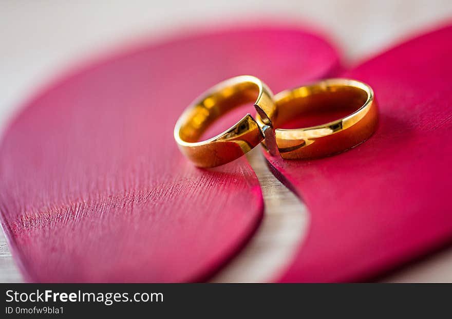 Two broken golden wedding rings on broken red heart. Divorce concept