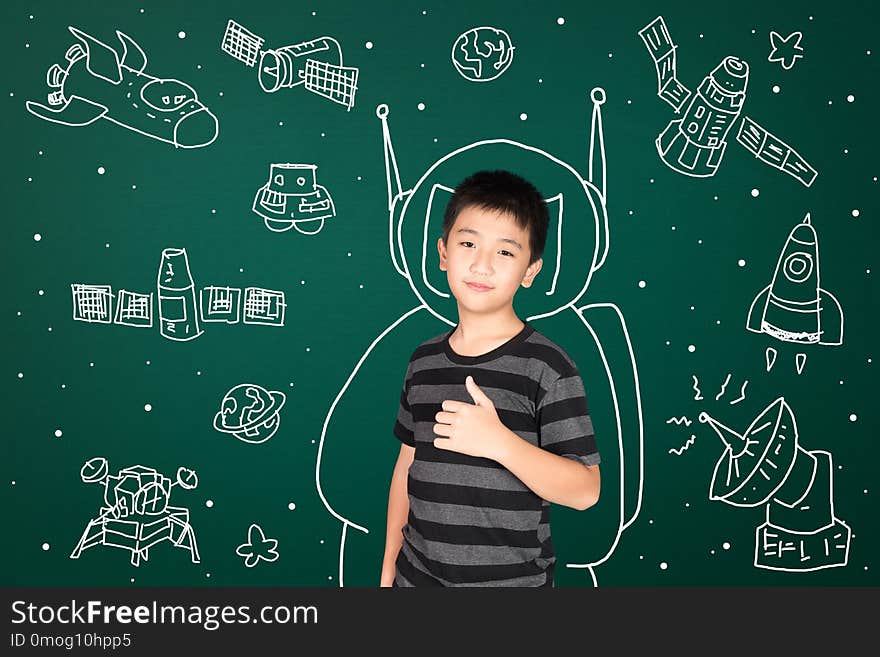 Asian kid with his imagination about science and space adventure, hand drawn on the green chalkboard, education back to school and discovery concept idea.