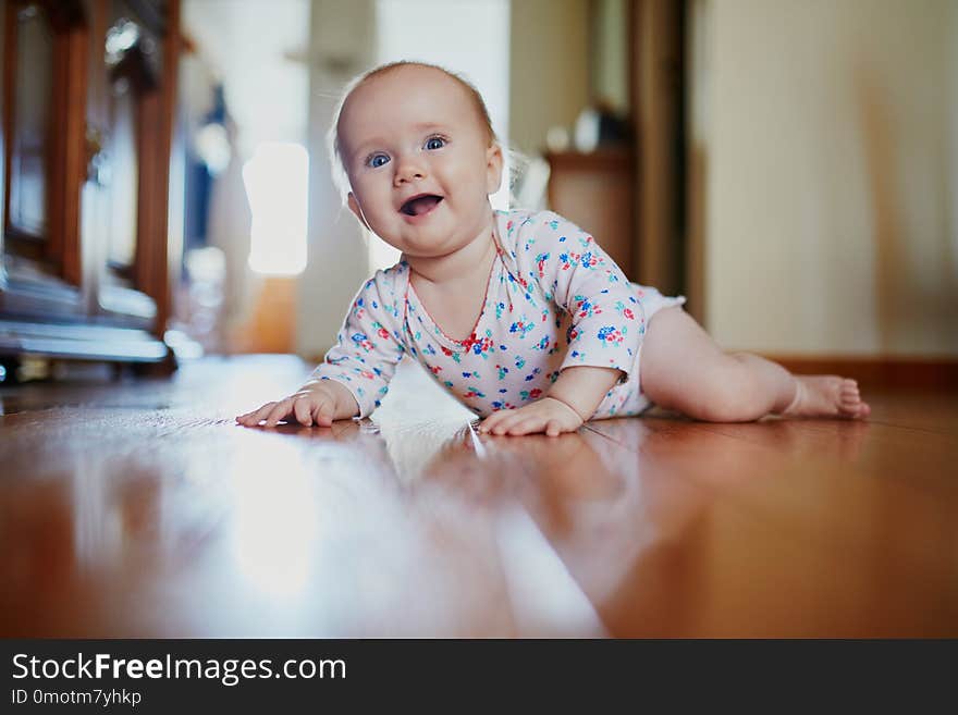 Baby girl learning to crawl. Happy healthy little child on the floor. Infant kid at home