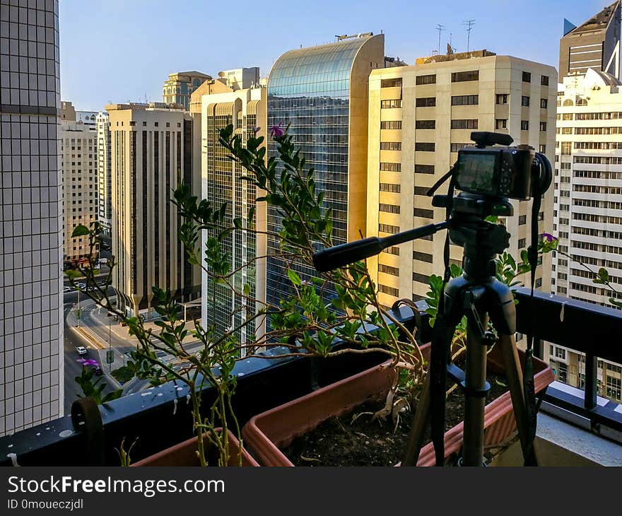 Shooting a time lapse of the sunset in a balcony in the city - camera and tripod.