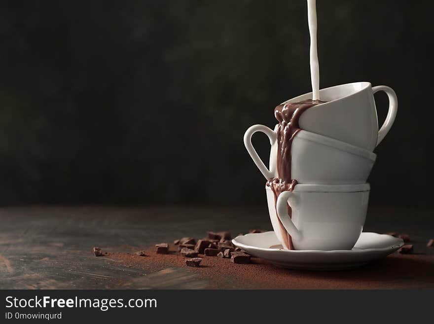 Adding milk to tasty hot chocolate on table