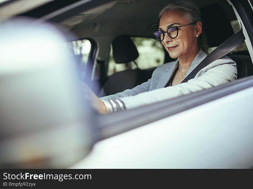 Mature businesswoman concentrating on road while driving a car. Senior female entrepreneur traveling to work in her car. Mature businesswoman concentrating on road while driving a car. Senior female entrepreneur traveling to work in her car.