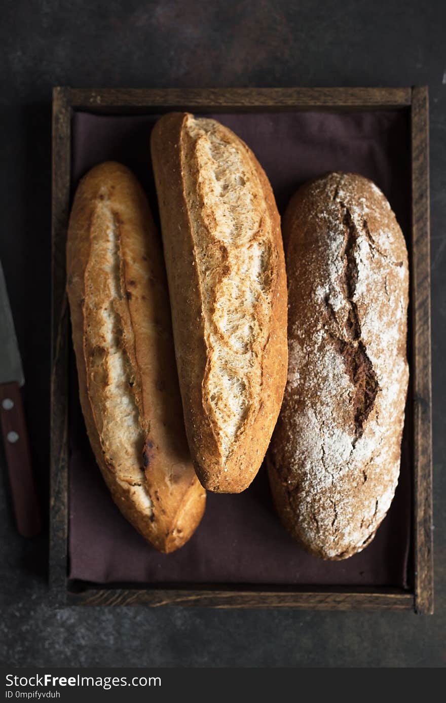 Various fresh homemade bread in rustic wooden box, top view, copy space. Sourdough mini baguette wheat and rye bread. Various fresh homemade bread in rustic wooden box, top view, copy space. Sourdough mini baguette wheat and rye bread.