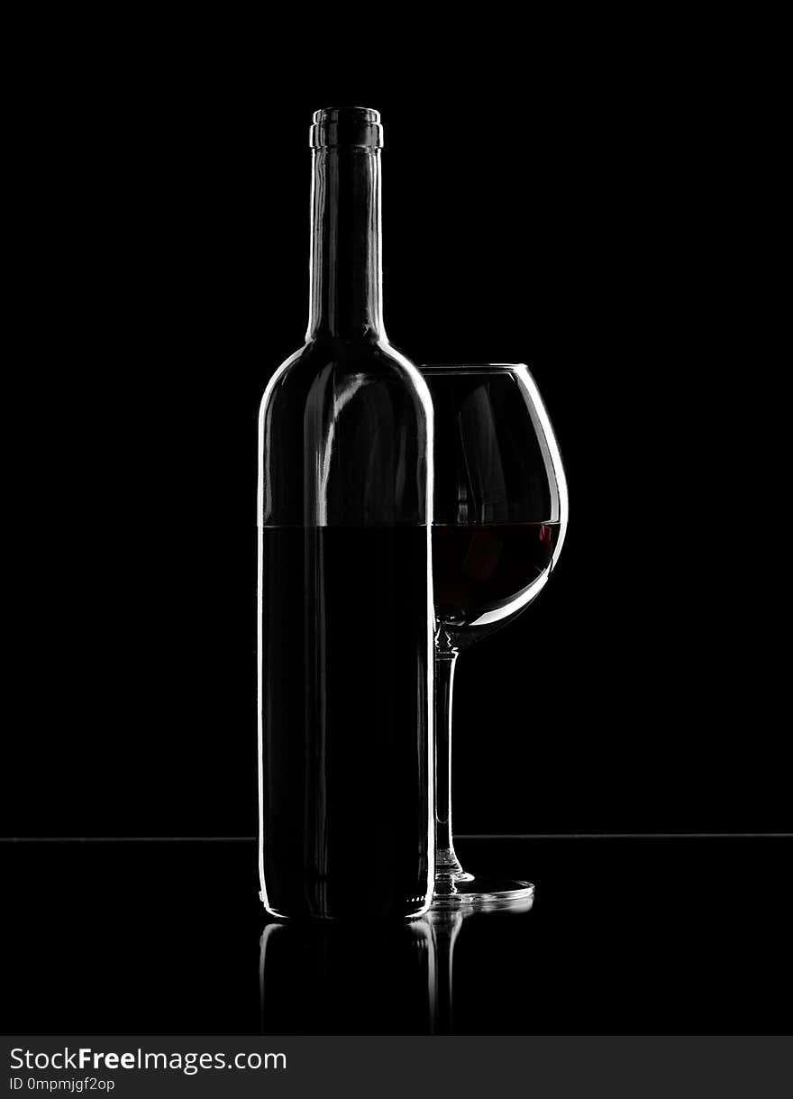 Bottle and wine glass with red wine, photo on black background. Bottle and wine glass with red wine, photo on black background