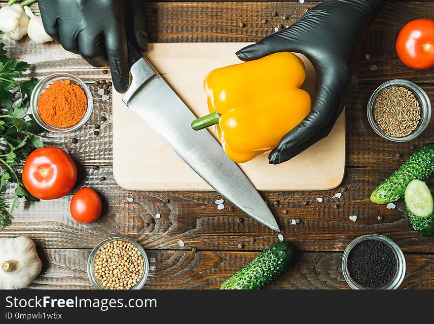 Women`s hands cut paprika, close to tomatoes, herbs, cucumbers. Horizontal frame