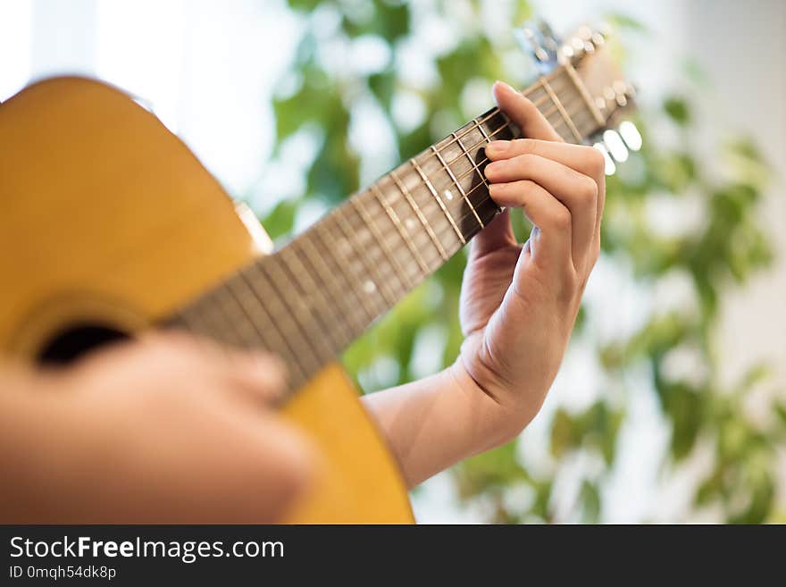 To play the acoustic guitar. Male hand on the deck and the edge of the guitar in the frame