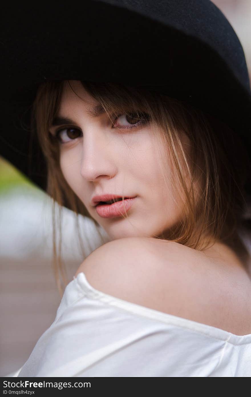 Closeup portrait of attractive young model wearing black hat posing at the city