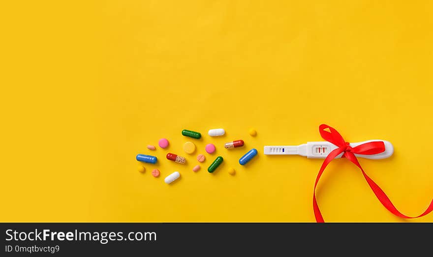 Pregnancy test, pills and vitamins on a yellow background. Health of the child and mother.