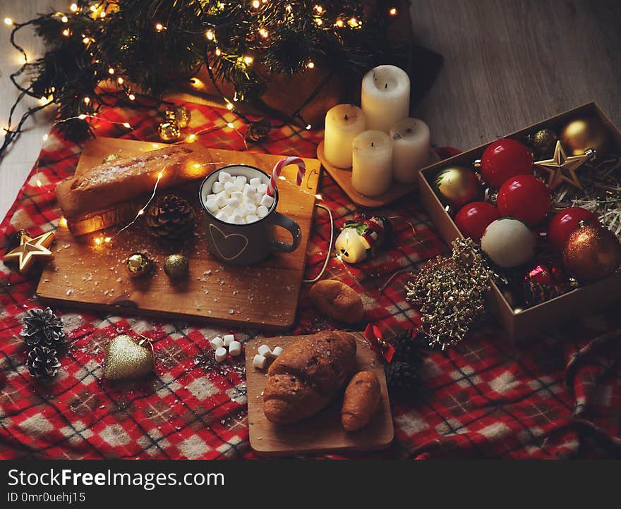 New Year`s dinner in red and gold tones with cocoa candles, a festive cupcake and croissants. New Year`s dinner in red and gold tones with cocoa candles, a festive cupcake and croissants