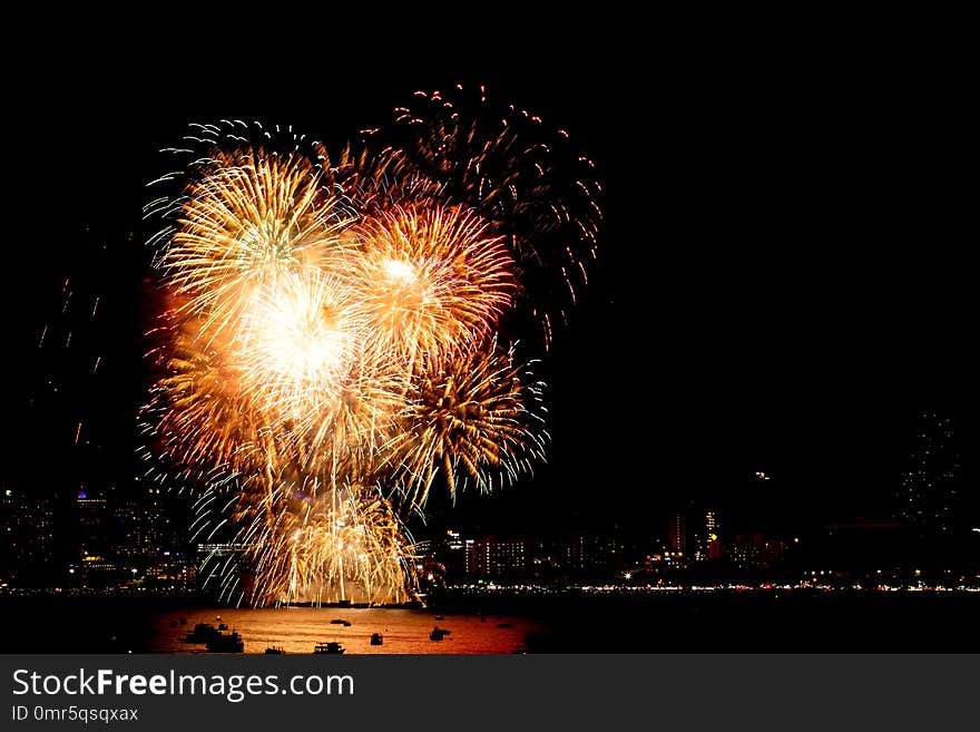 Many flashing fireworks with night cityscape background celebrate New Year.