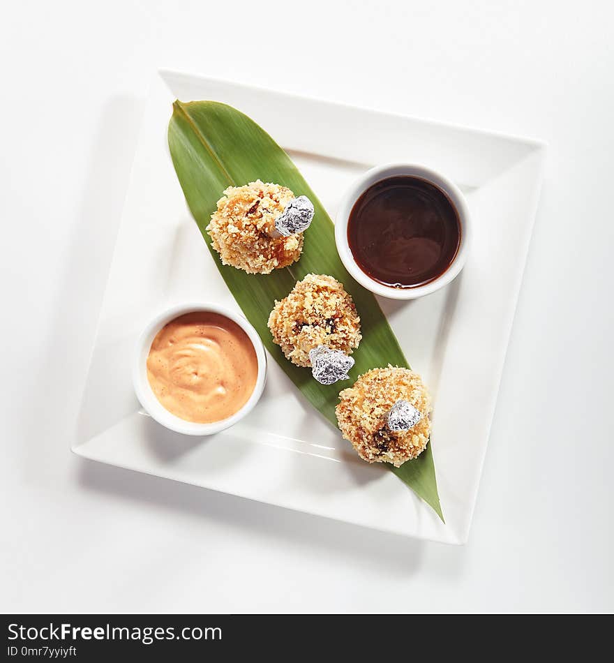 Restaurant Main Course with Deep Fried Crispy Chicken Legs, Thighs or Drumstick on a Banana Leaf with Sauces . Exquisite Serving Breaded Crunchy Nuggets Made of Poultry Meat Top View. Restaurant Main Course with Deep Fried Crispy Chicken Legs, Thighs or Drumstick on a Banana Leaf with Sauces . Exquisite Serving Breaded Crunchy Nuggets Made of Poultry Meat Top View