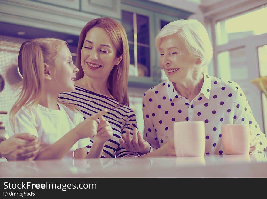 Our gladness. Pleased young woman embracing her child while being in all ears. Our gladness. Pleased young woman embracing her child while being in all ears