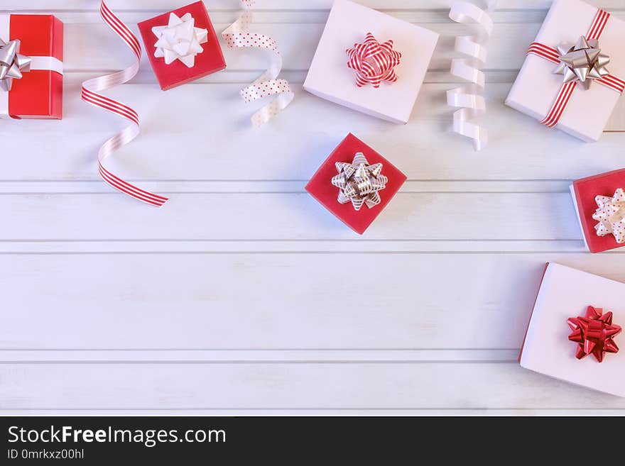 Red and white gift boxes with beautiful bows, decorative ribbons. Christmas composition with place for text, copy space. Festive photo on a pale blue background.