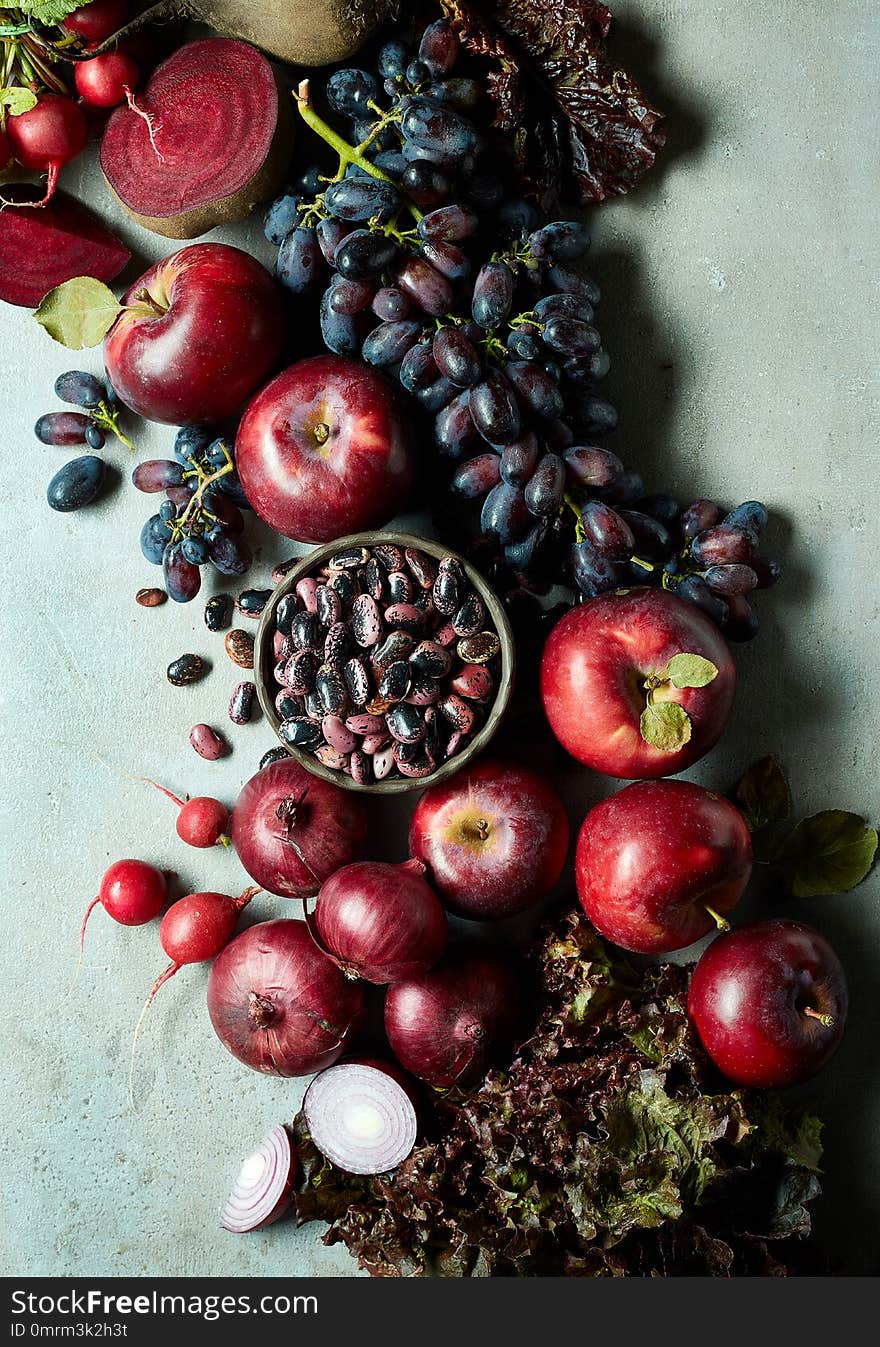 Fresh various pink, red and purple fruits and vegetables on gray marble background. Top view