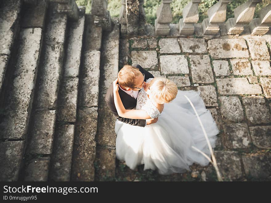 Beautiful fairytale newlywed couple hugging near old medieval castle.