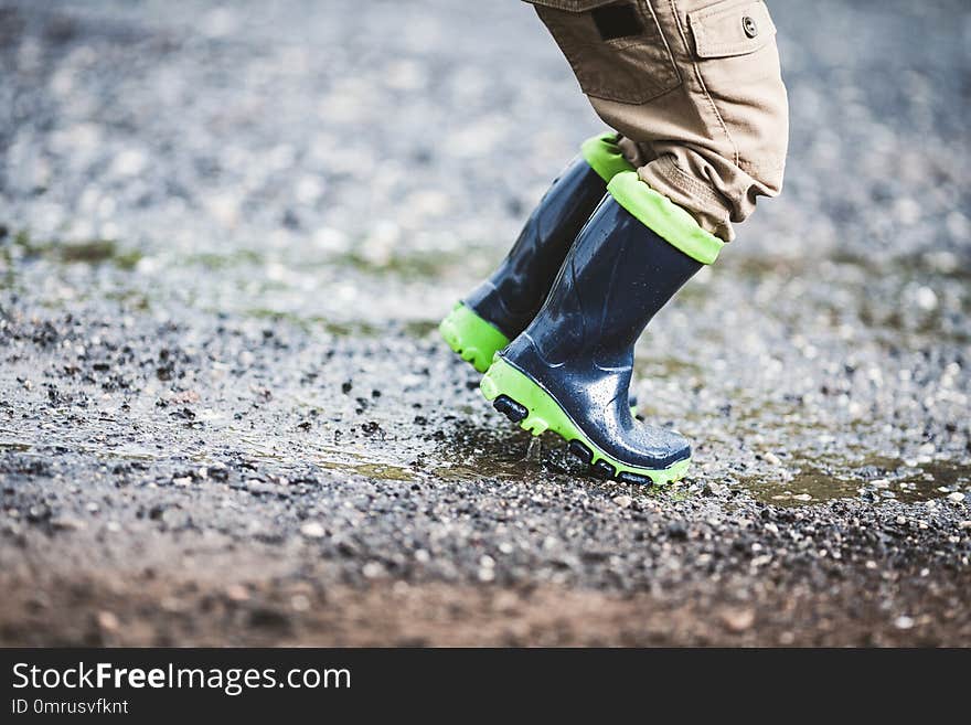 Close up on toddler wearing rubber boots in rainy weather