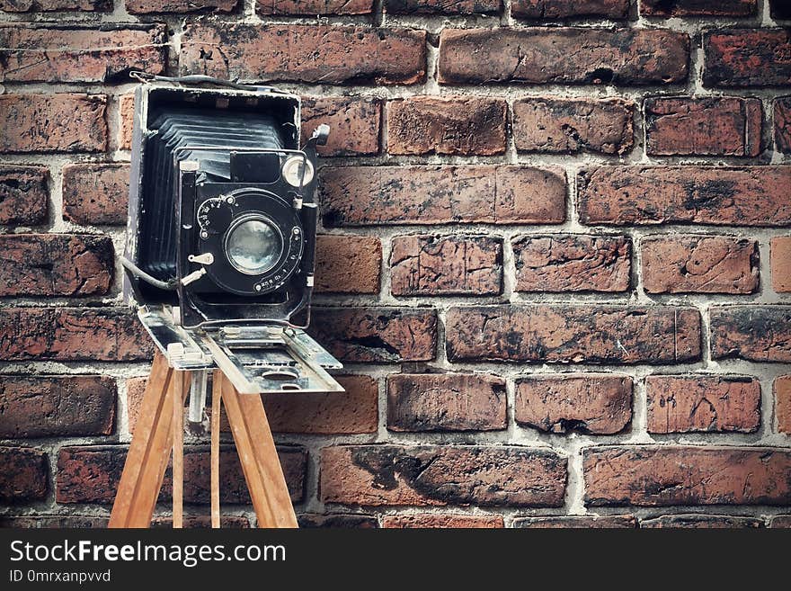 Old vintage camera against a brick wall. Concept photo studio. Copy space.