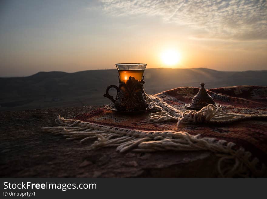 Eastern black tea in glass on a eastern carpet. Eastern tea concept. Armudu traditional cup. Sunset background. Selective focus