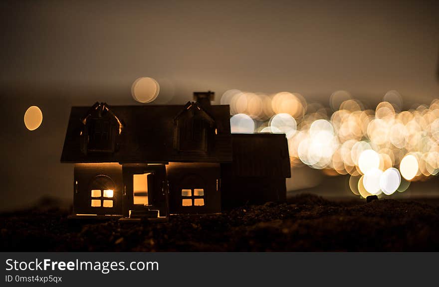 Little decorative house, beautiful festive still life, cute small house at night, Night city real bokeh background, happy winter holidays. Selective focus