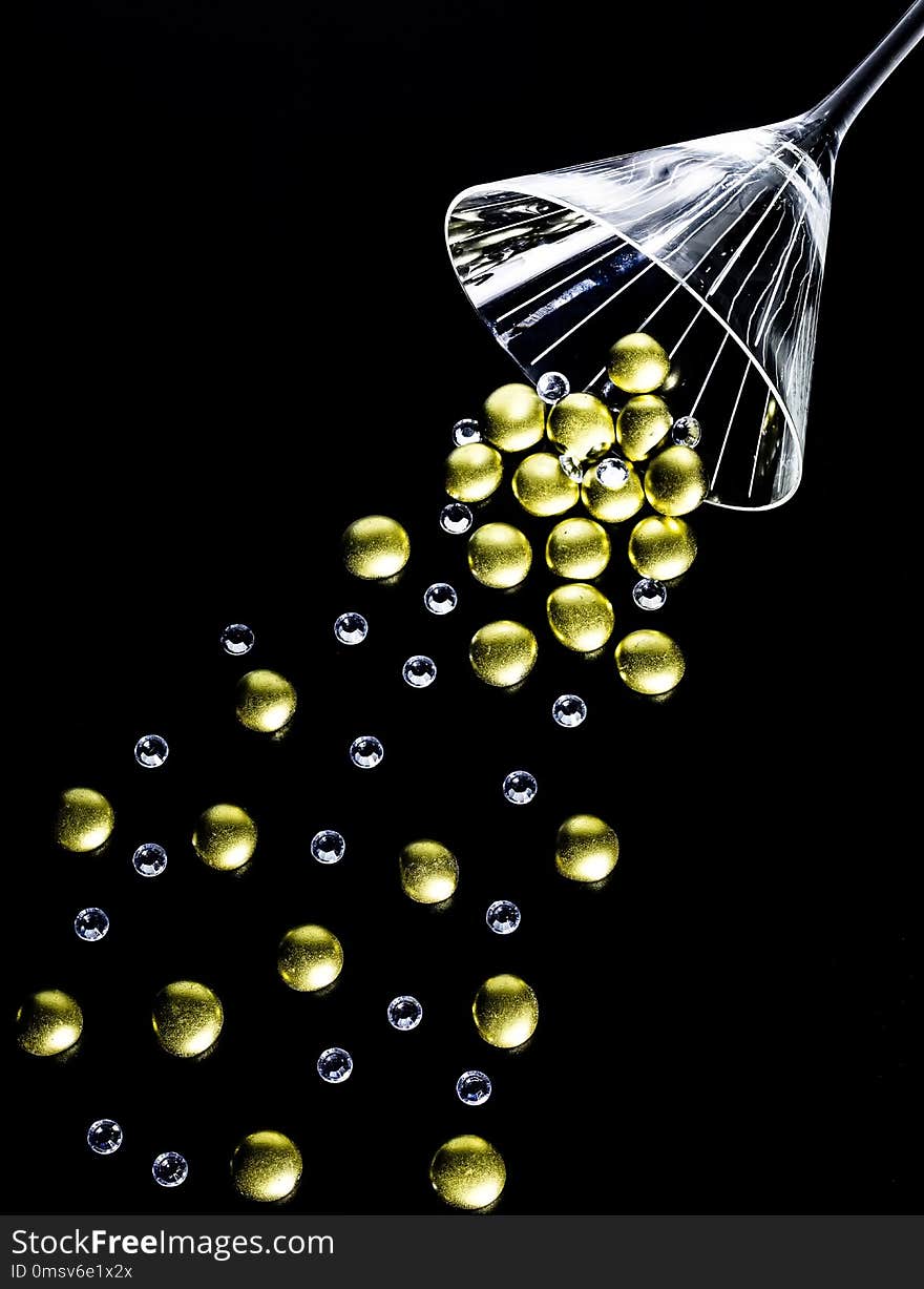 Golden nuggets and crystals spilling out of a martini glass. Golden nuggets and crystals spilling out of a martini glass.