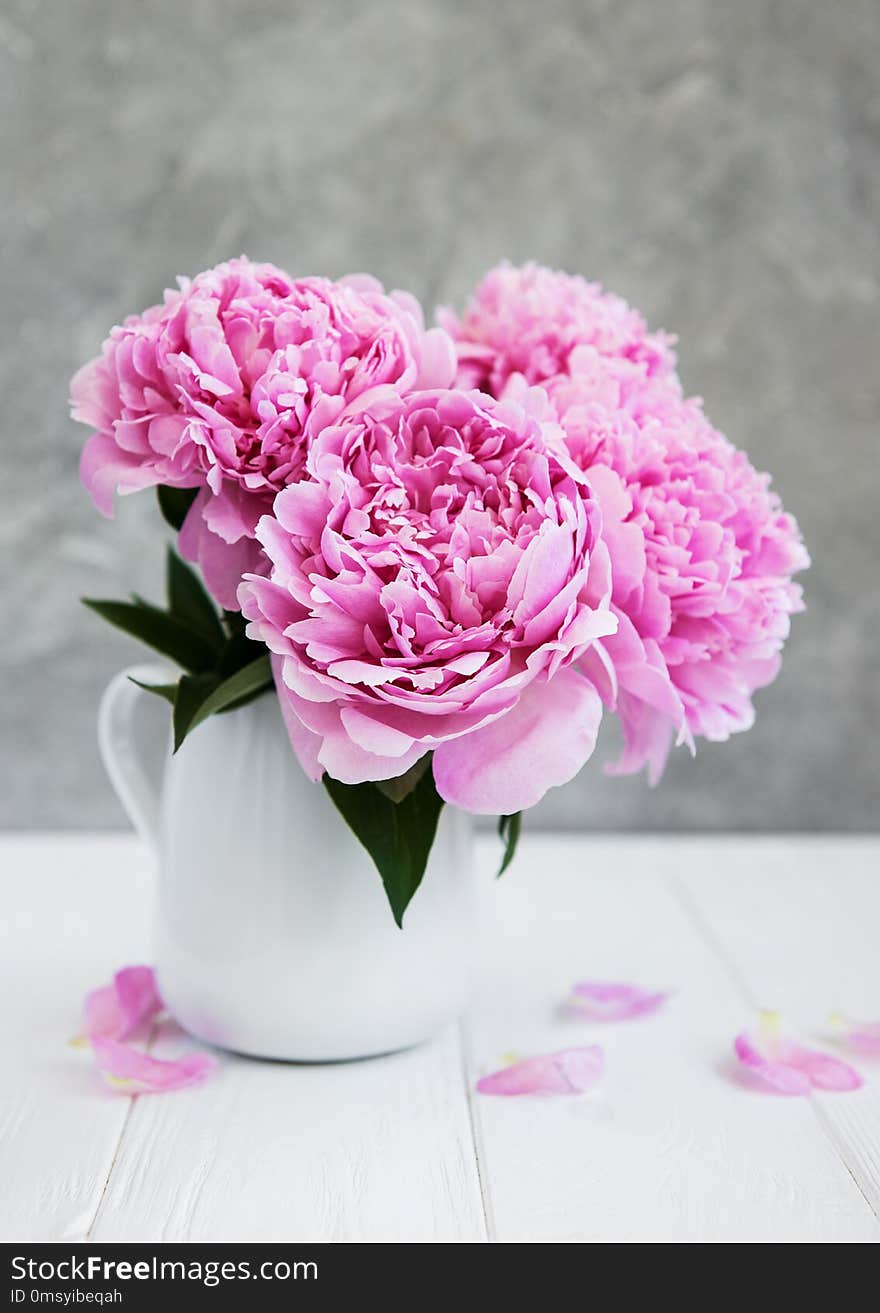 Vase with pink peony flowers on a white wooden table