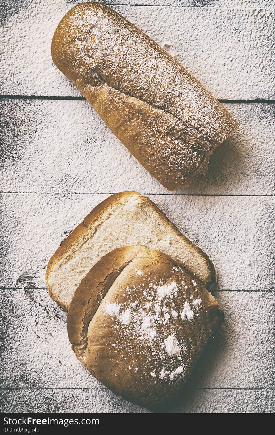 Bakery concept. Sliced bread and loaf of bread on a table with flour.