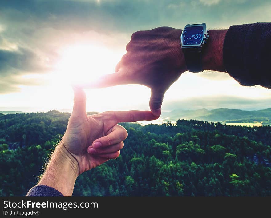 Palms with fingers making a frame sign over misty landscape