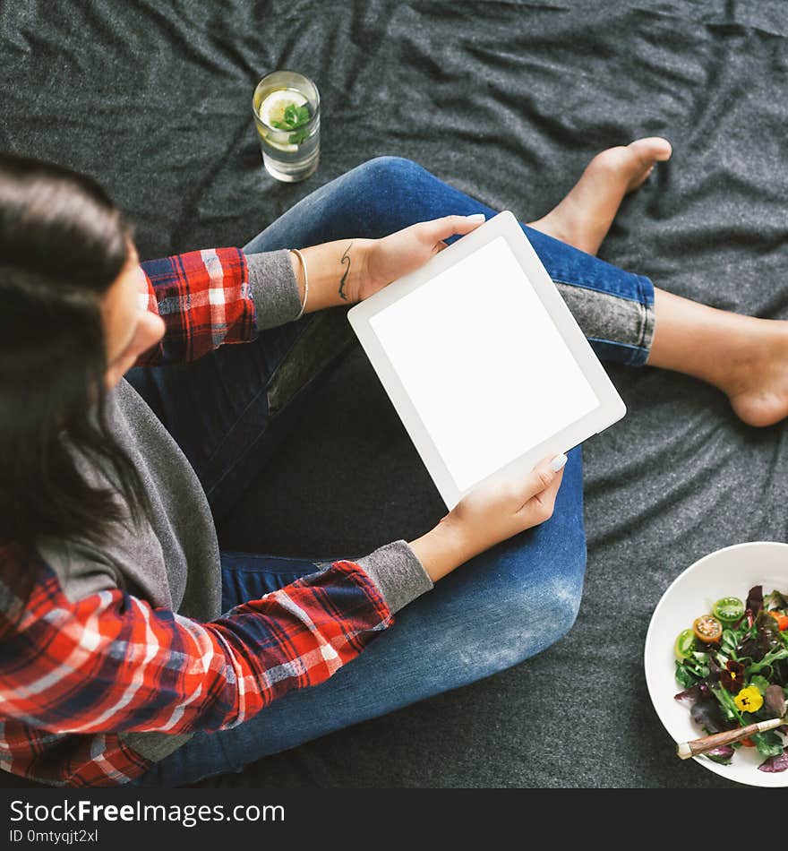 Woman hands holding digital tablet with empty blank screen sitting on bed, top view. Woman hands holding digital tablet with empty blank screen sitting on bed, top view