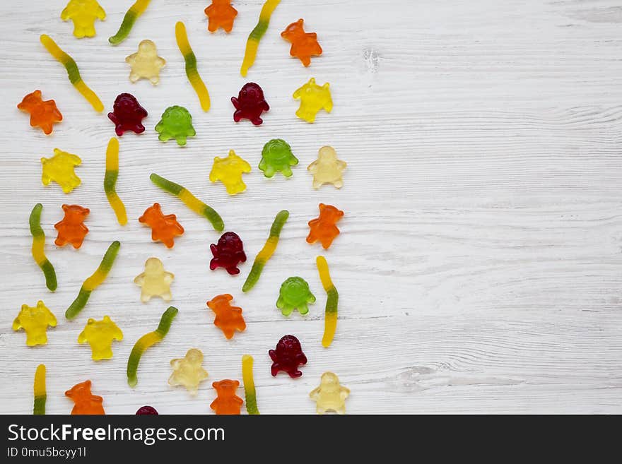 Jelly monsters and worms on a white wooden background, top view. From above, overhead. Copy space