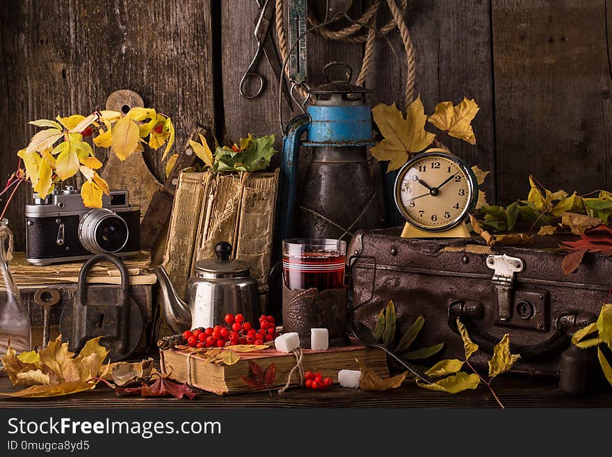 Romantic autumn still life with books, vintage suitcase, old clock and leaves. Vintage still life