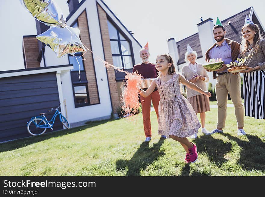 Be active. Kind girl holding balloons while running with pleasure. Be active. Kind girl holding balloons while running with pleasure