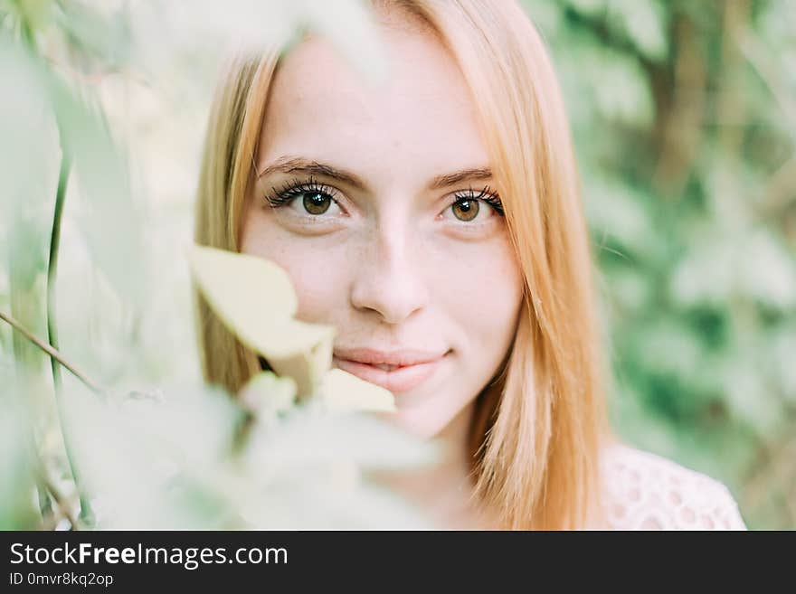 Beautiful attractive young woman posing in spring park wearing white knitted top and blue jeans, modern creative toning