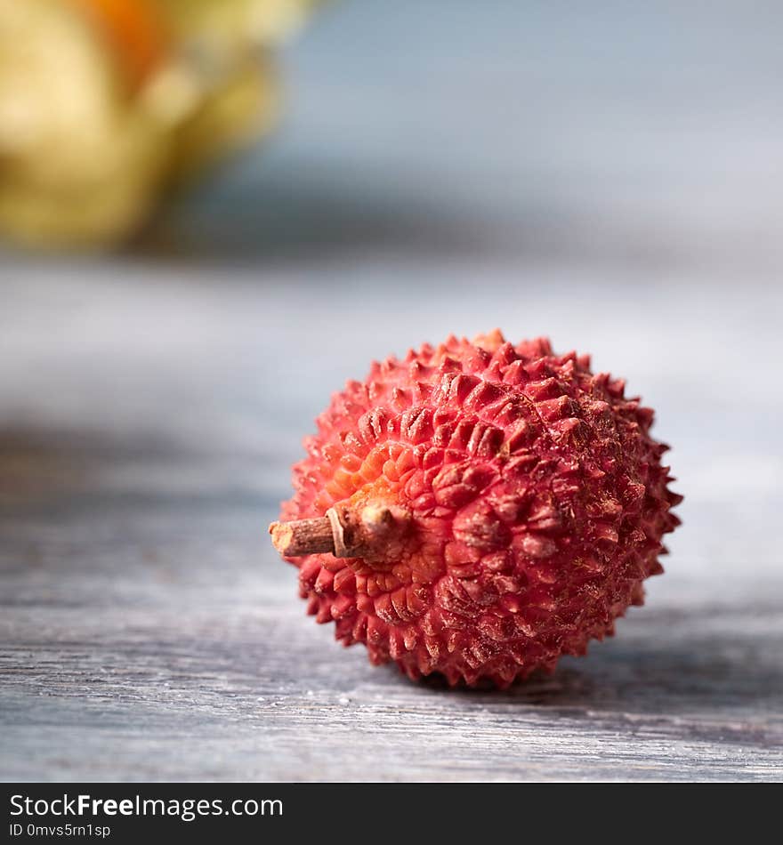 Tropical fresh fruit ripe litchi single on a gray wooden table with place for text. Close-up. Tropical fresh fruit ripe litchi single on a gray wooden table with place for text. Close-up.