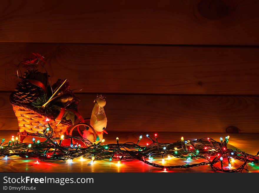 Christmas garland with a snowman in a sleigh with gifts. On wooden background.