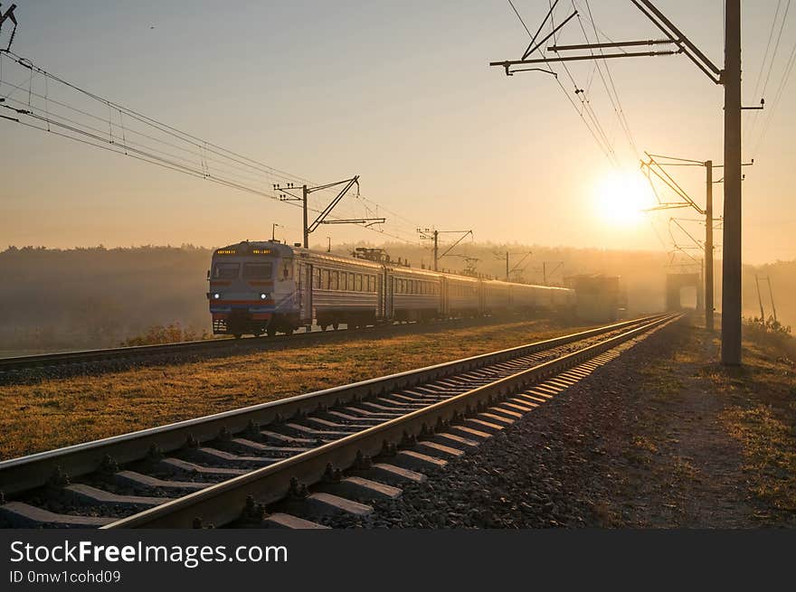 Passenger train on the railway bridge in autumn foggy morning.