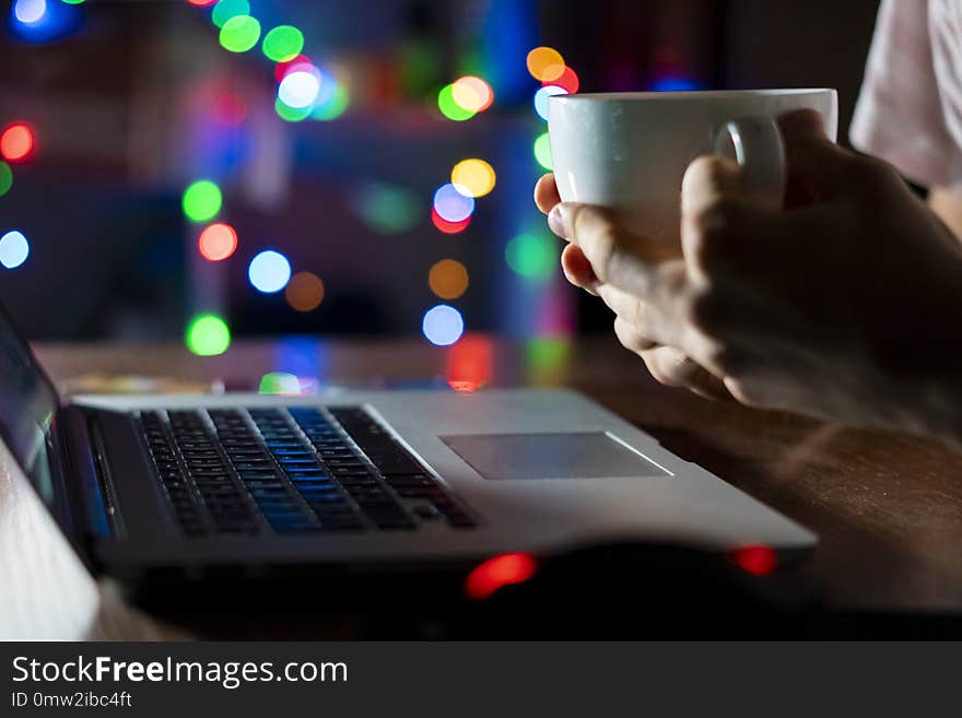 Night time worker in office sitting at the table using laptop and drink coffee f