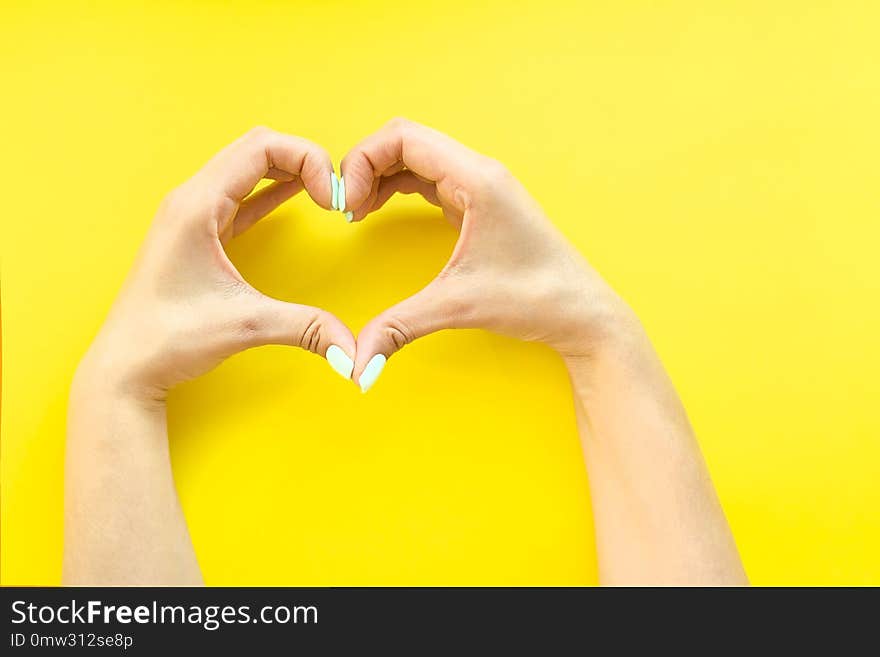 Heart from hands on a yellow background