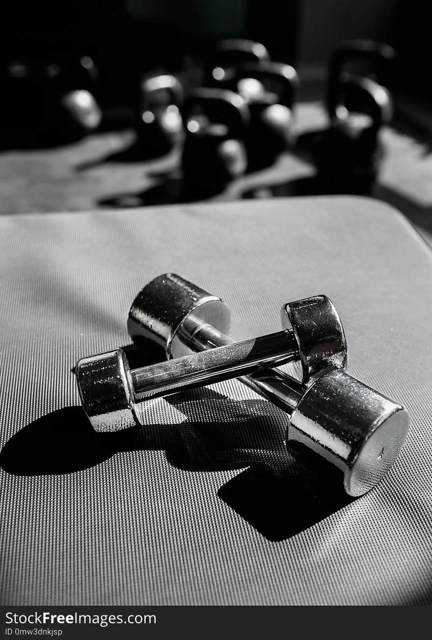 Chrome-plated dumbbells lying on a rubber floor in gym