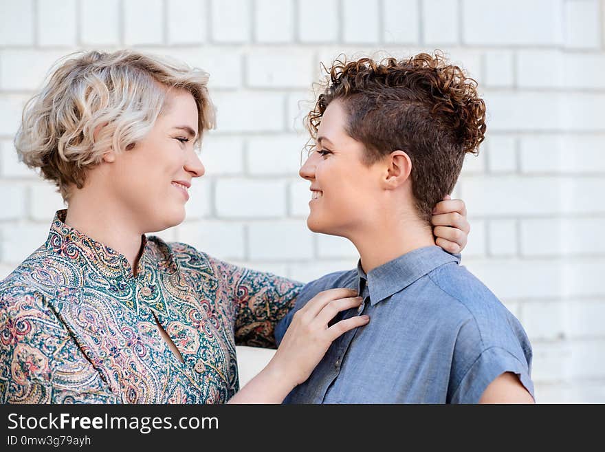 Affectionate young lesbian couple looking lovingly into each other`s eyes while standing together on a city street outside. Affectionate young lesbian couple looking lovingly into each other`s eyes while standing together on a city street outside