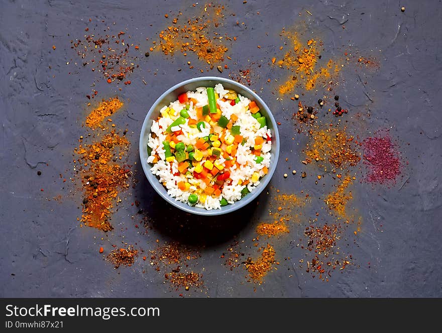 Rice with vegetables and spices on dark blue concrete background. Vegetarian food, products for proper nutrition, close up