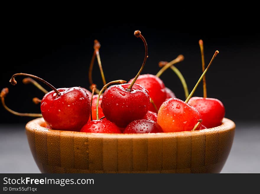 Photo of sweet cherry in wooden cup on gray table