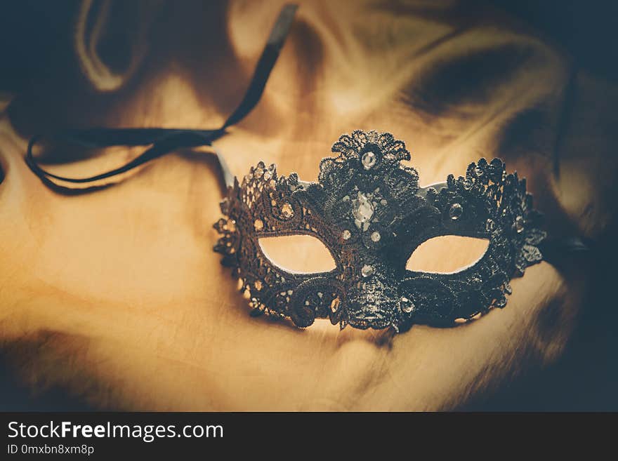 Luxury venetian ball mask on golden silk fabric. Masquerade vintage party or holiday event celebration concept. Luxury venetian ball mask on golden silk fabric. Masquerade vintage party or holiday event celebration concept.