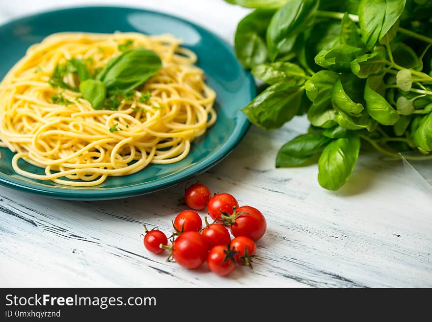 Pasta with herbs, basil and fresh tomatos served on green pate in rustic kitchen. Pasta with herbs, basil and fresh tomatos served on green pate in rustic kitchen